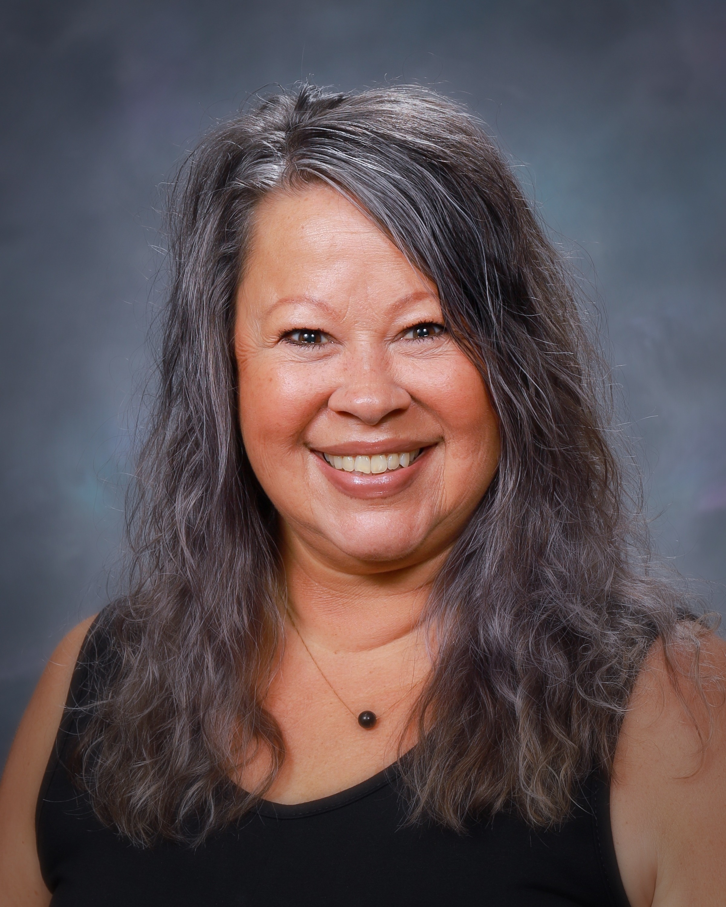 A women with long dark hair smiles at the camera.